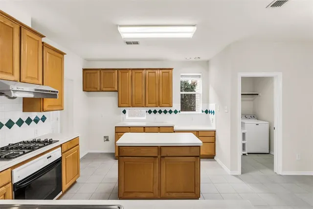 a utility room with stainless steel appliances granite countertop a stove a sink and a refrigerator