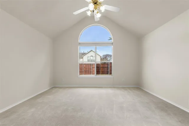 an empty room with a chandelier fan and windows