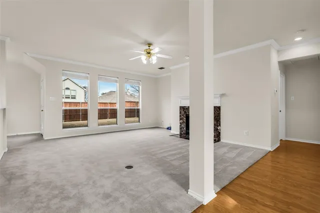 an empty room with chandelier fan and windows