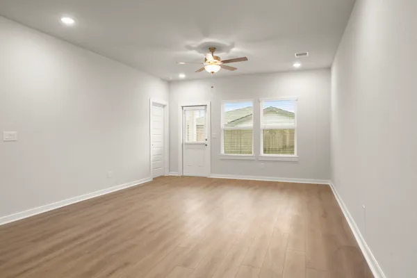 a view of an empty room with a window and wooden floor