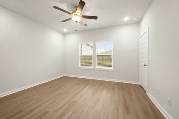 an empty room with wooden floor and windows