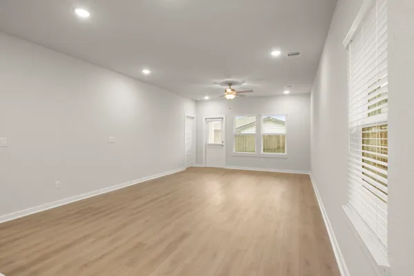 a view of an empty room with wooden floor and a window
