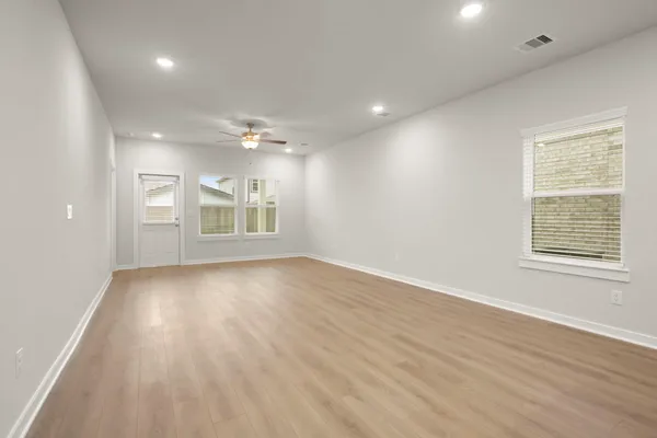 an empty room with wooden floor and windows