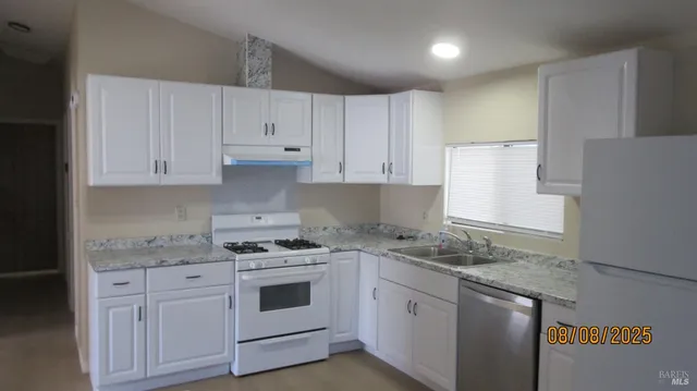 a kitchen with granite countertop white cabinets and white appliances