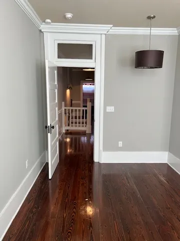 a view of a hallway with wooden floor and a living room