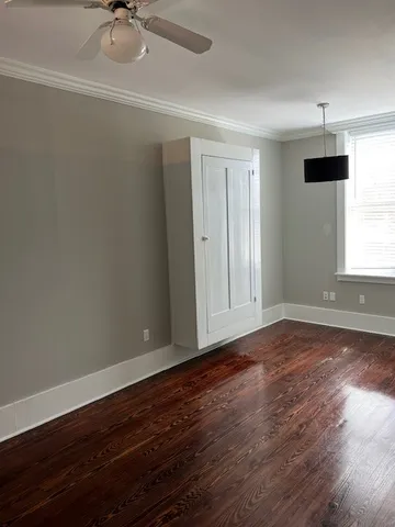 a view of an empty room with a window and wooden floor