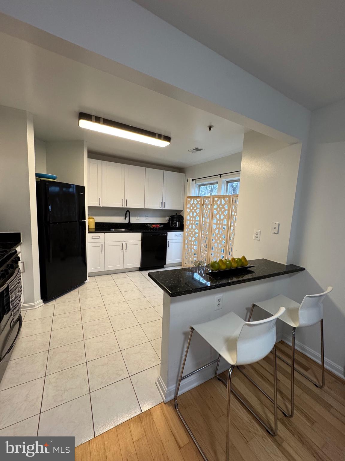 18310 Feathertree Way, Unit 101 Montgomery Village, MD 20886 - Photo 31 of 31 a kitchen with stainless steel appliances kitchen island granite countertop a table chairs in it and wooden floors