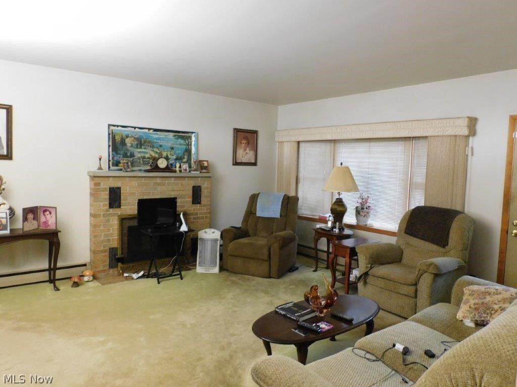 5853 Shepard Road Ashtabula, OH 44004 - Photo 6 of 27 Living room featuring baseboard heating, carpet, and a brick fireplace