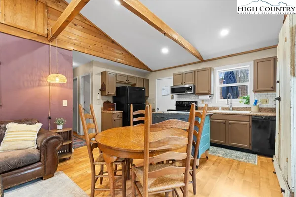 a kitchen with stainless steel appliances granite countertop a stove a sink dishwasher a dining table and chairs with wooden floor