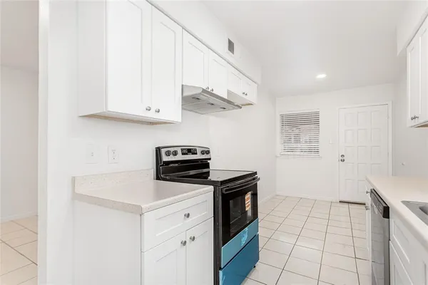 a kitchen with white cabinets and appliances