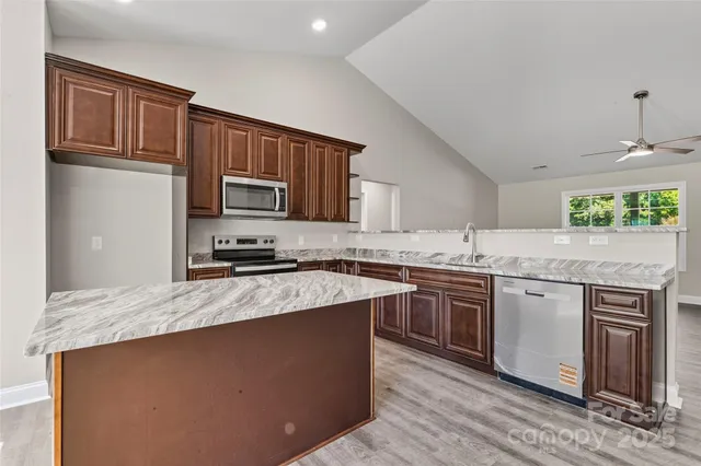 a kitchen with stainless steel appliances granite countertop a stove top oven a sink dishwasher and wooden cabinets