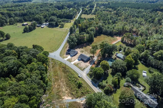 an aerial view of a house with a yard lake and trees all around