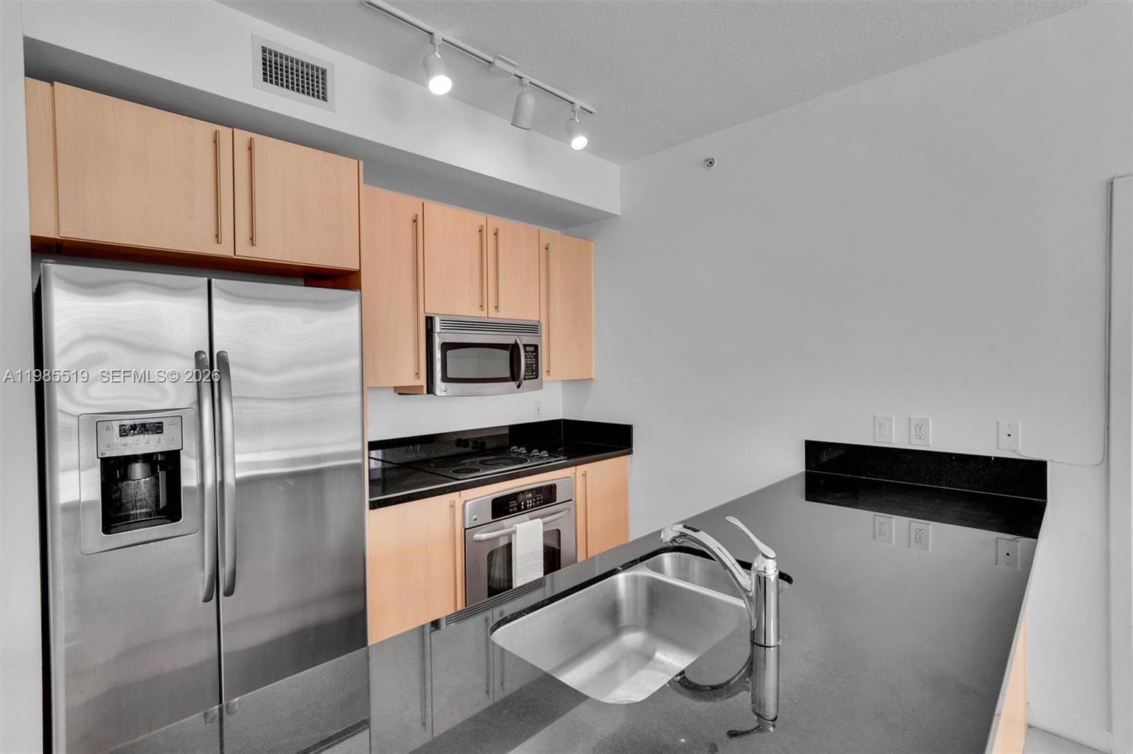 79 Southwest 12th Street, Unit 1210 Miami, FL 33130 - Photo 3 of 37 a kitchen with stainless steel appliances granite countertop a refrigerator a sink and white cabinets
