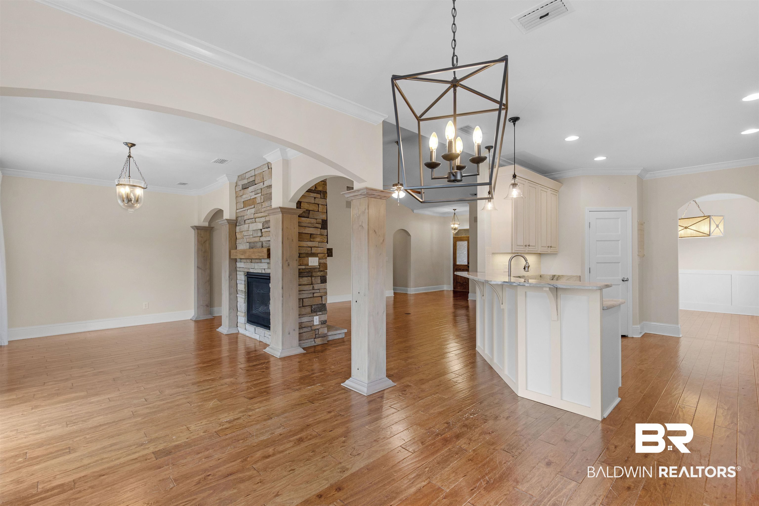 25092 Fairfax Road Daphne, AL 36526 - Photo 10 of 29 Kitchen featuring crown molding, hanging light fixtures, a notable chandelier, light hardwood / wood-style floors, and a stone fireplace