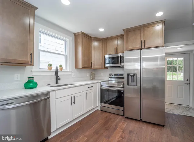 a kitchen with kitchen island granite countertop a sink stainless steel appliances and window