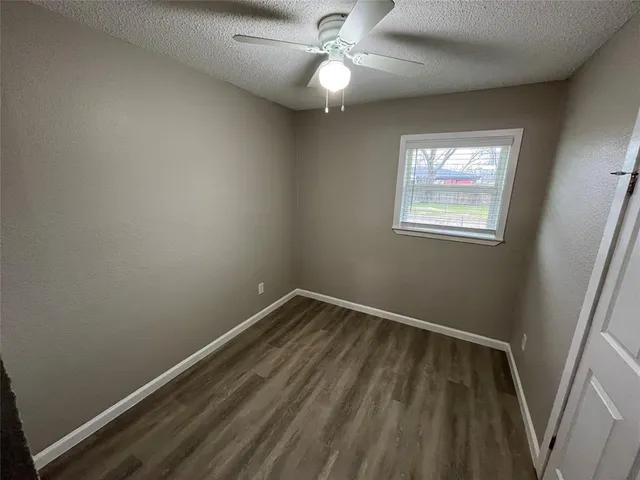 an empty room with a window and a fan