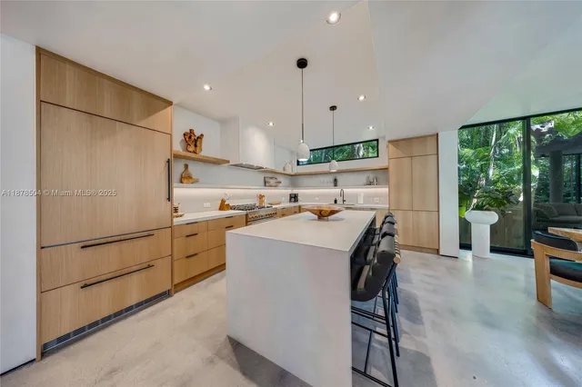 a kitchen with kitchen island a stove a refrigerator and a dining table with wooden floor