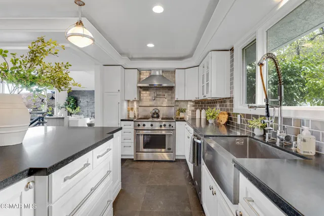 a kitchen with stainless steel appliances granite countertop a sink a stove and a refrigerator