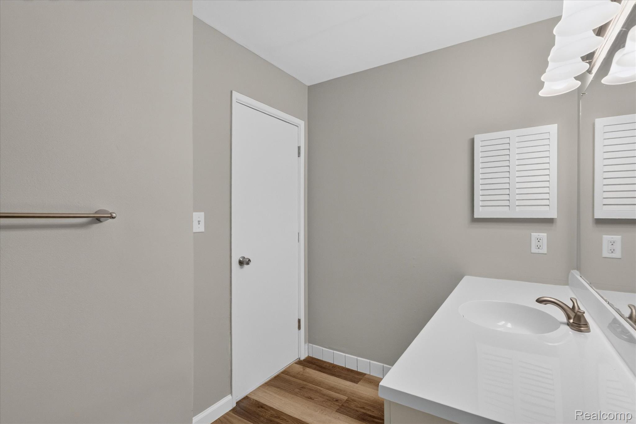 32650 Mound Road, Unit 4 Warren, MI 48092 - Photo 21 of 32 Wood-finish flooring, white vanity with integrated sink, brushed nickel faucet, and a wall-mounted louvered cabinet