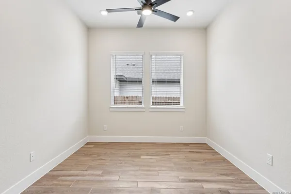 a view of empty room with wooden floor and fan