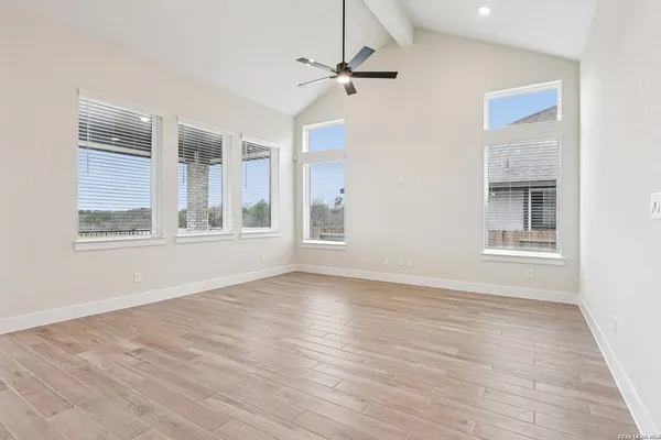 a view of an empty room with a window and wooden floor