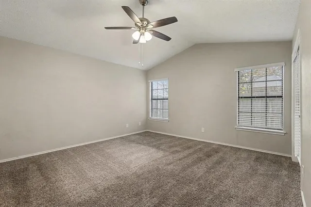 an empty room with windows and ceiling fan