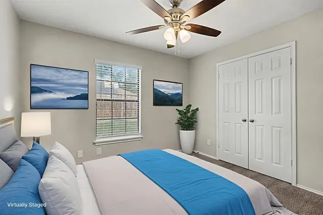 a bedroom with a large bed and a chandelier fan
