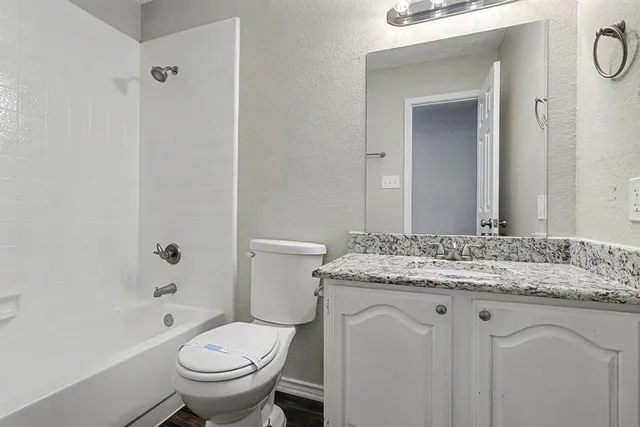 a bathroom with a granite countertop toilet a sink and a bathtub