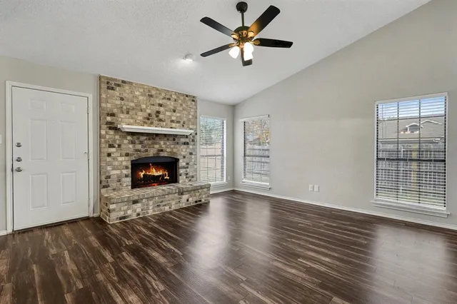 a view of an empty room with wooden floor fireplace and a window