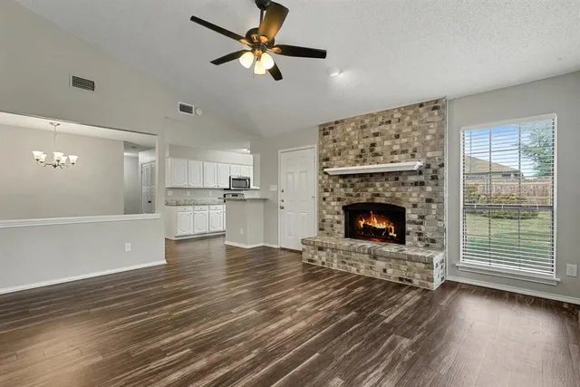 a view of a livingroom with a fireplace a ceiling fan and windows