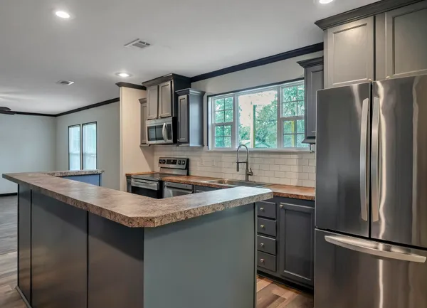 a kitchen with stainless steel appliances granite countertop a refrigerator a sink a stove and a refrigerator