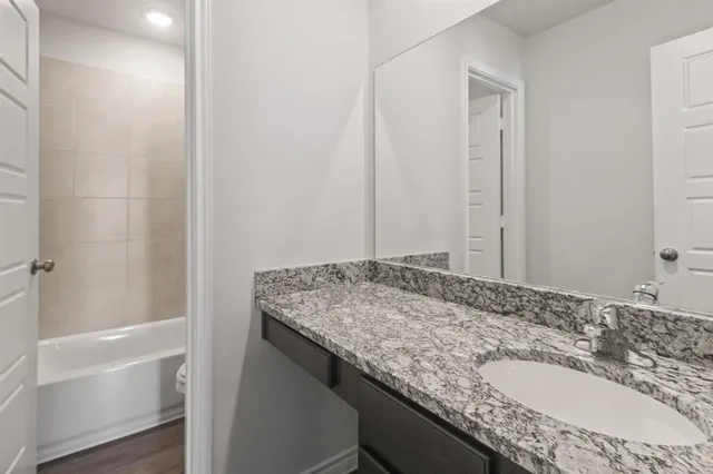 a bathroom with a granite countertop sink and a bathtub