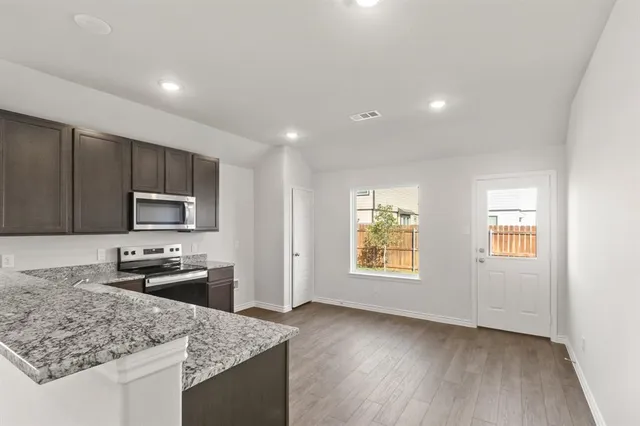 a kitchen with stainless steel appliances granite countertop a sink stove microwave and refrigerator