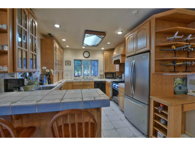 3852 Higuera Road San Jose, CA 95148 - Photo 8 of 25 a kitchen with stainless steel appliances kitchen island granite countertop a refrigerator a stove and a sink with wooden cabinets