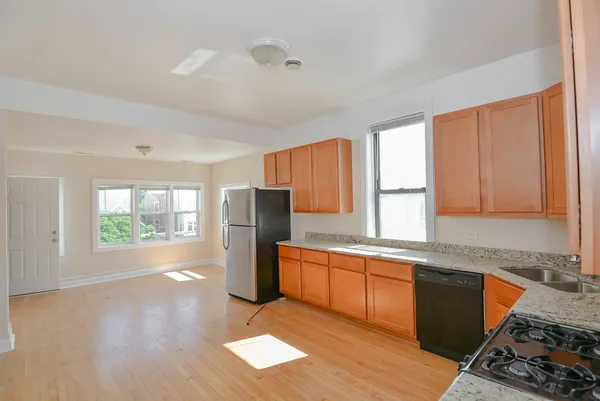 a kitchen with stainless steel appliances granite countertop a refrigerator a sink dishwasher a stove with wooden cabinets and floor