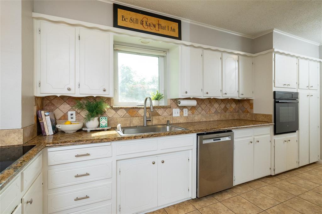 205 Timberlake Drive Azle, TX 76020 - Photo 8 of 40 a kitchen with granite countertop white cabinets white appliances and a sink