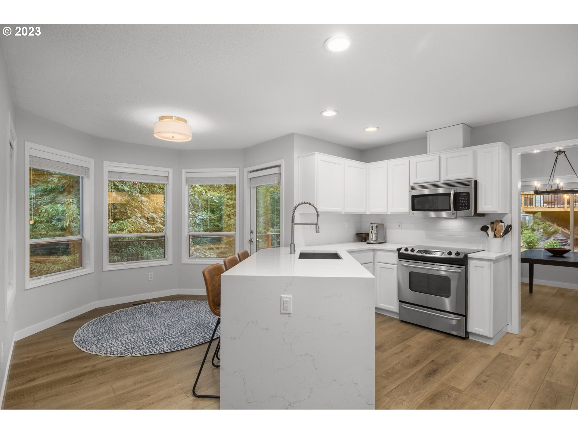 4806 Southwest Orchard Lane Portland, OR 97219 - Photo 8 of 35 a kitchen with stainless steel appliances granite countertop a stove a sink a microwave a refrigerator and white cabinets with wooden floor