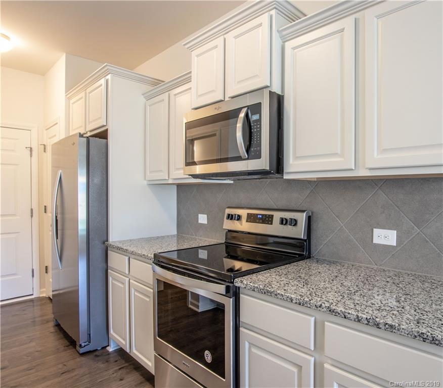 12532 Gotland Road, Unit 331 Midland, NC 28107 - Photo 11 of 26 a kitchen with stainless steel appliances granite countertop white cabinets and a stove top oven