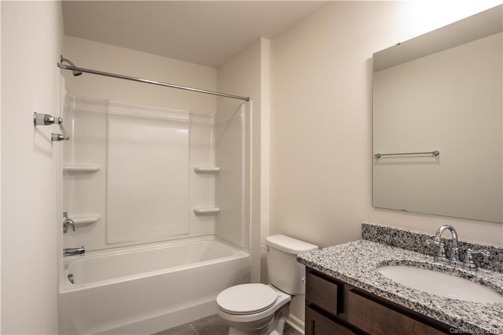 12532 Gotland Road, Unit 331 Midland, NC 28107 - Photo 23 of 26 a bathroom with a granite countertop sink toilet a mirror and shower