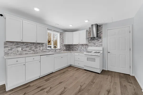 a kitchen with stainless steel appliances granite countertop a stove a sink and white cabinets