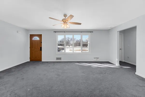 an empty room with windows and ceiling fan