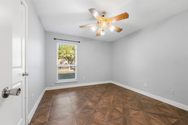 an empty room with windows and chandelier fan