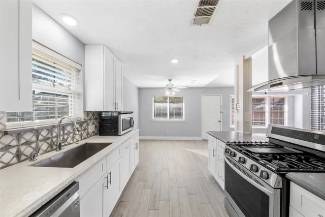 a kitchen with stainless steel appliances granite countertop a sink stove and wooden floor