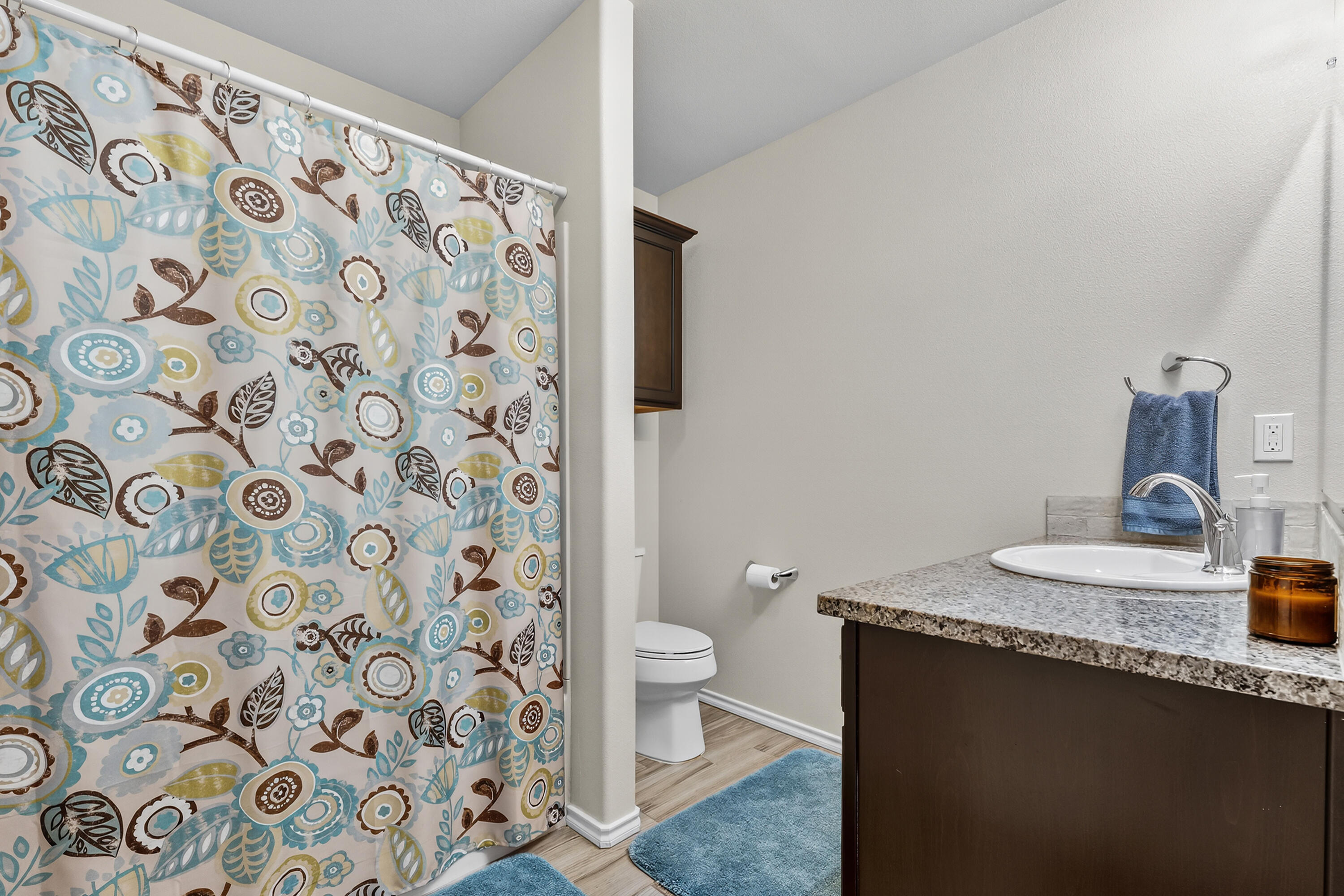 7402 105th Street Lubbock, TX 79424 - Photo 13 of 22 a bathroom with a granite countertop sink a toilet and a shower curtain