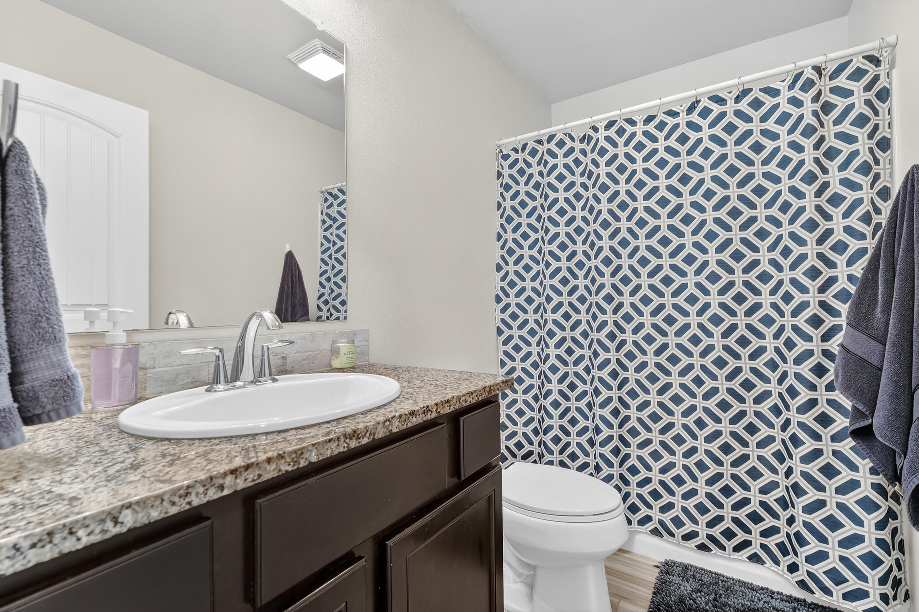 7402 105th Street Lubbock, TX 79424 - Photo 16 of 22 a bathroom with a sink a toilet and a mirror