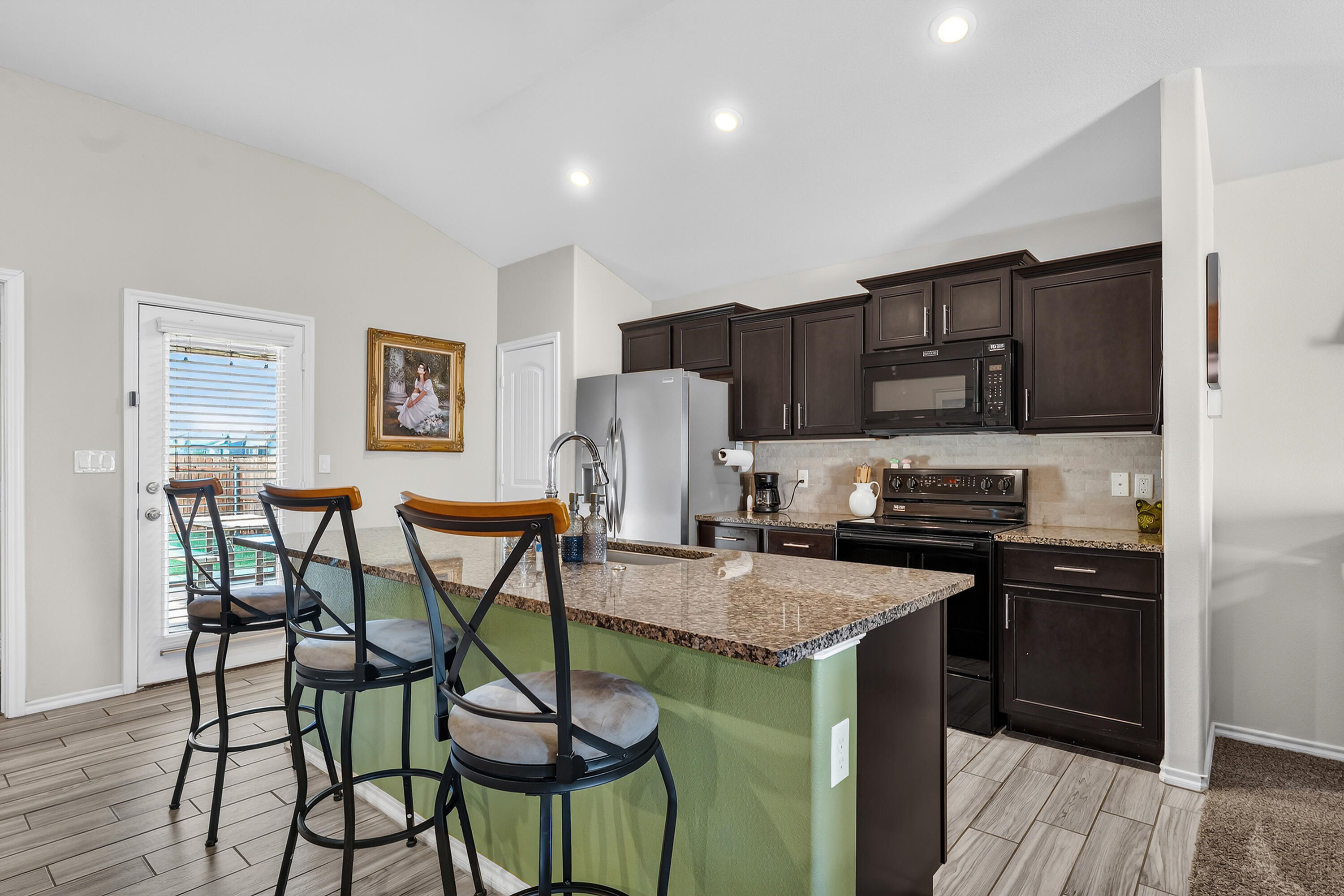 7402 105th Street Lubbock, TX 79424 - Photo 6 of 22 a kitchen with stainless steel appliances granite countertop a stove top oven a sink a refrigerator with a dining table and chairs