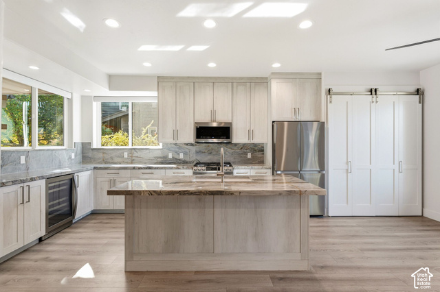 Kitchen with large center island, stainless steel appliances, recessed lighting, wood-finish flooring, and a barn door entry