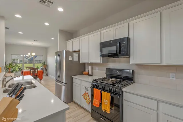 a kitchen with stainless steel appliances granite countertop a stove a refrigerator a sink a microwave and cabinets