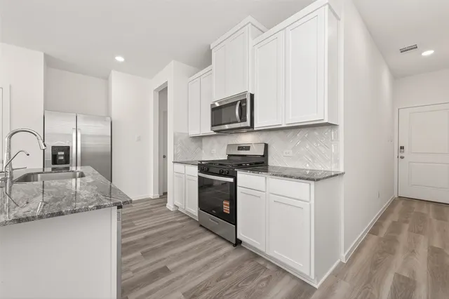 a kitchen with stainless steel appliances granite countertop a stove a sink and a microwave