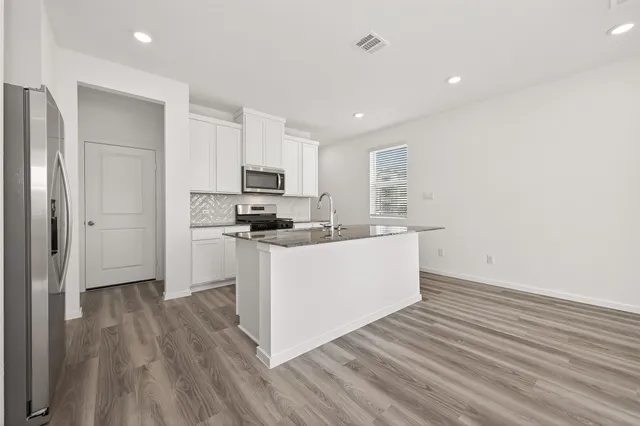 a kitchen with wooden floors white cabinets and stainless steel appliances
